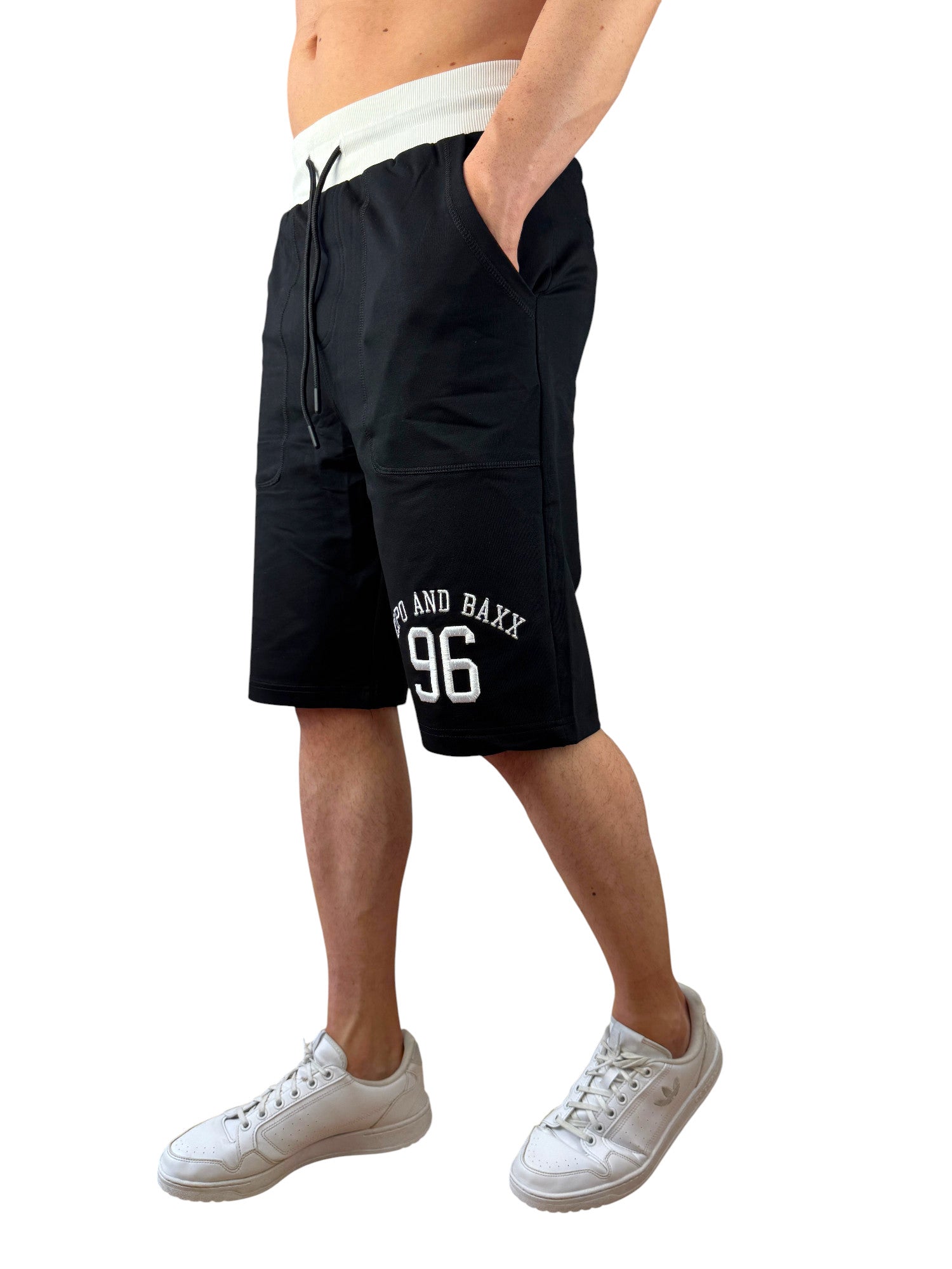 Ein schwarzer Cipo und Baxx Sweat Capri Short für Männer mit weißen Bestickungen auf dem linken Bein und weißem Bund